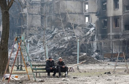 Dos personas descansan en un banco cerca de un edificio de apartamentos destruido en Mariupol. La vice primera ministra de Ucrania, Irina Vereshchuk, ha comunicado esta mañana que se ha acordado con la parte rusa habilitar 10 corredores humanitarios que estarán abiertos a lo largo de este sábado para evacuar a los civiles de los puntos de acceso de primera línea en pueblos y ciudades de Ucrania.