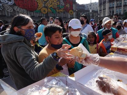 Decenas de personas hacen fila para recibir un pedazo de rosca de reyes, en el Zócalo de Ciudad de México, el 6 de enero de 2023.