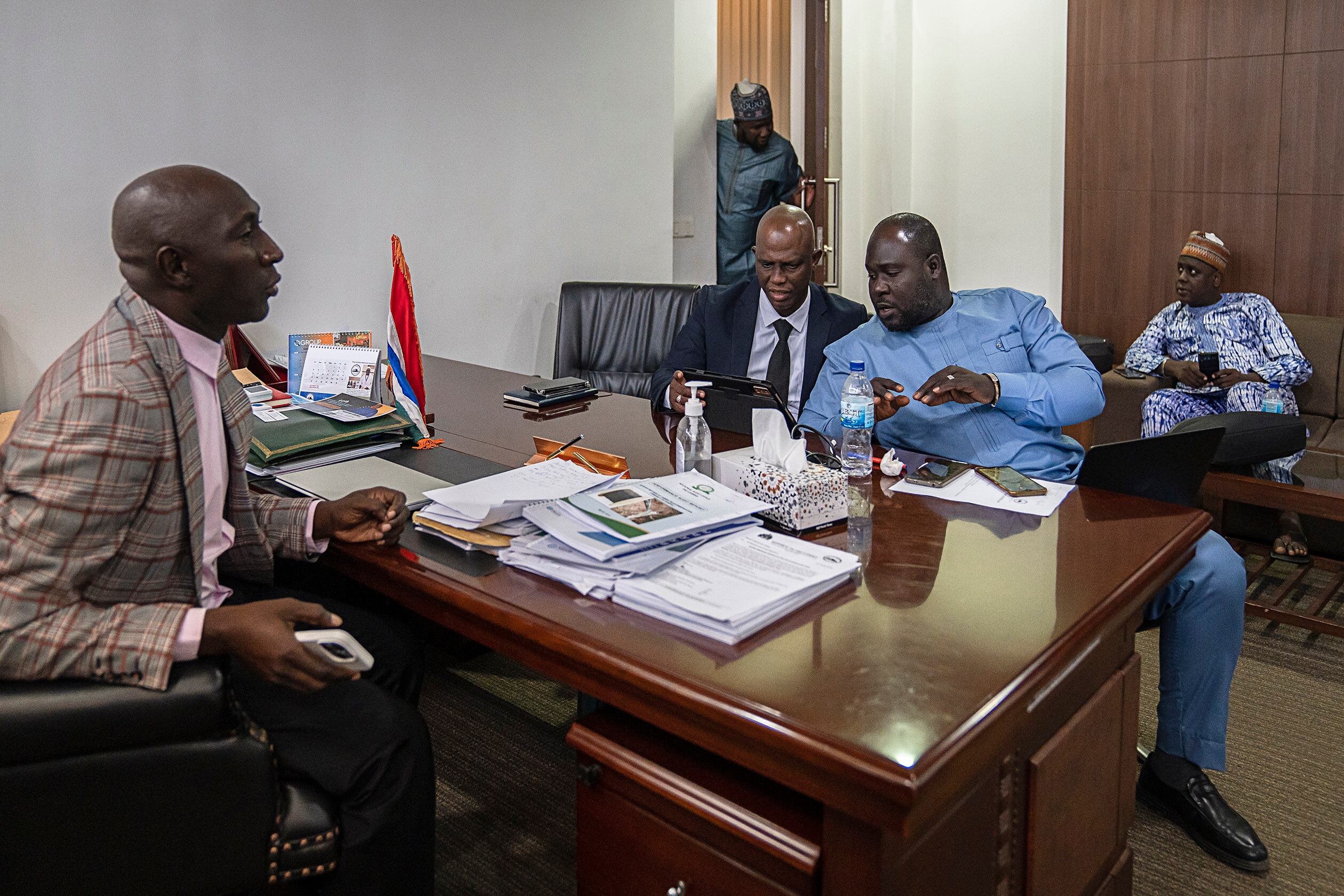 El diputado Gibbi Mballow (izquierda) votó en contra del proyecto de ley para eliminar la prohibición de la ablación. En la imagen, en su despacho del Parlamento con diputados de su partido, el del Gobierno, en Banjul. 