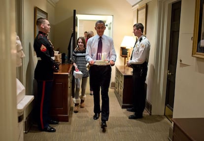 2 de diciembre de 2013. Junto con la hija del jefe de Gabinete, Denis McDonough, Obama lleva una tarta de cumpleaños para sorprender a McDonough en su oficina de West Wing en la Casa Blanca.