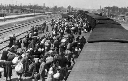 Chegada de deportados a Auschwitz. Ao fundo, as chaminés dos fornos crematórios.