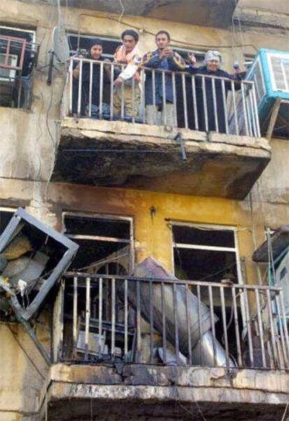 Vecinos observan los daños en su edificio tras un atentado ayer en Bagdad.