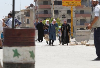 Un grupo de gente camina hacia el último puesto de control, bajo el dominio de las fuerzas del Gobierno sirio, en los suburbios de Damasco, Siria.