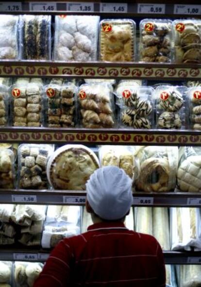 Un empleado ante un lineal con productos de bollería en una tienda de Madrid.