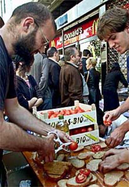 Miembros de grupos antiglobalización preparan pan con tomate ante un McDonald's en Gràcia.