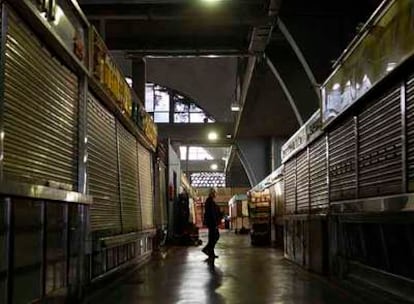 Un hombre camina entre los puestos cerrados del mercado de La Cebada, en pleno horario comercial.