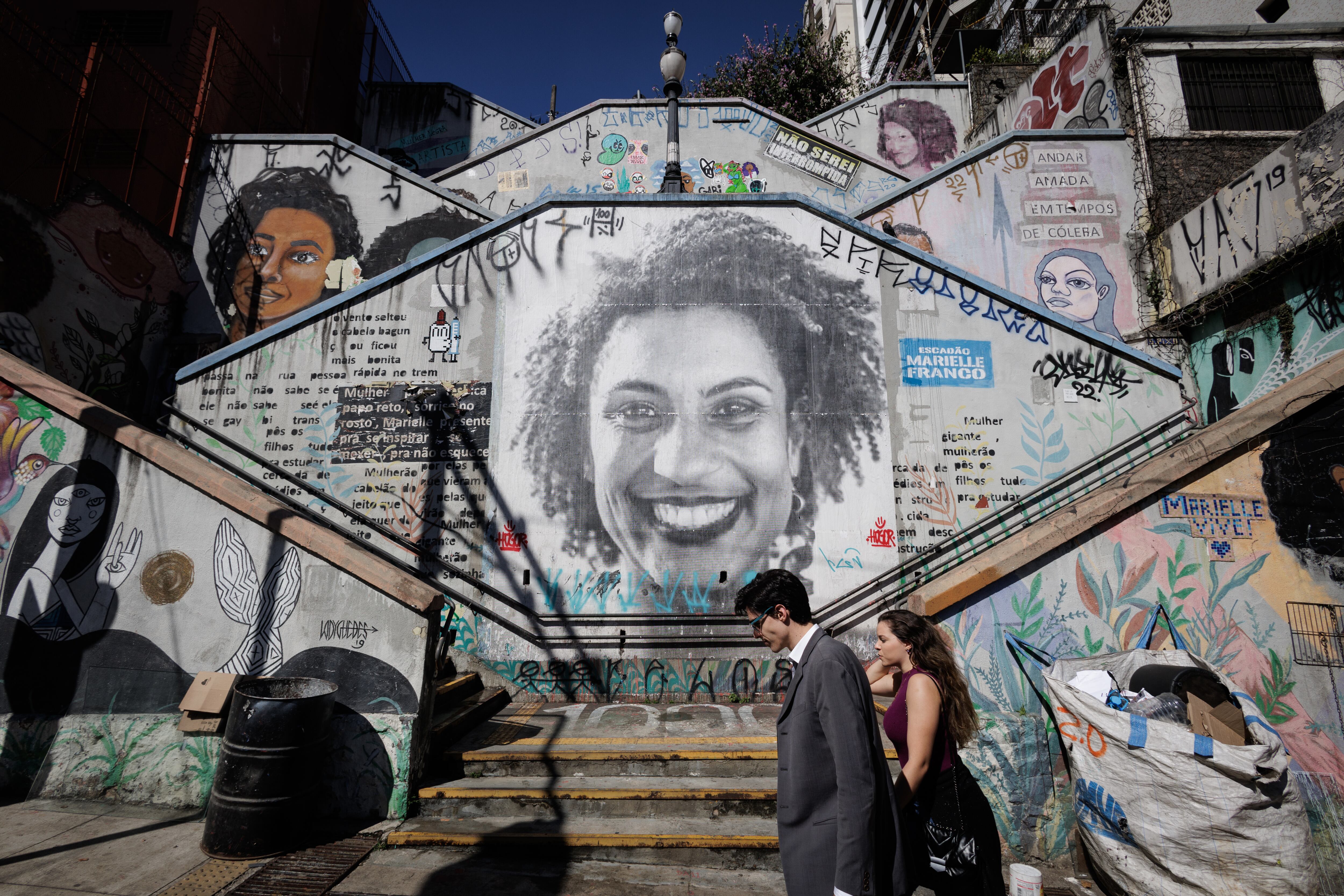 Dos personas caminan frente a un mural dedicado a Marielle Franco en São Paulo.