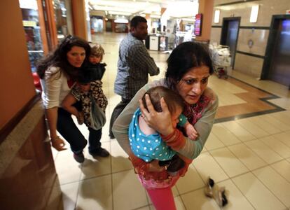 Nairobi, Kenia, 21 de septiembre de 2013. El Ejército de Kenia combatió planta por planta contra los terroristas atrincherados de Al Shabab en el centro comercial de Westgate, en Nairobi. En la imagen, una mujer lleva en brazos a un niño en pleno enfrentamiento en el interior del edificio.