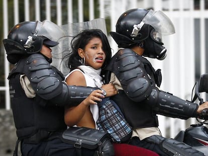 Members of the Venezuelan National Police arrest a woman who was participating in a march