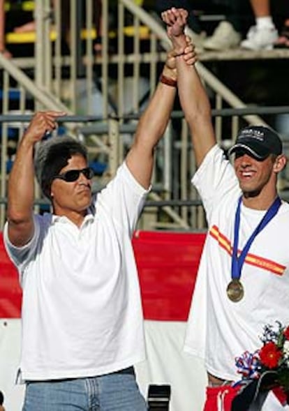 Mark Spitz levanta el brazo de Phelps tras el triunfo de éste en los 200 mariposa.