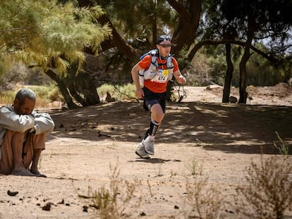 Un competidor pasa junto a un habitante local, durante la etapa 3 de la 34ª edición del 'Marathon des Sables', entre Kourci Dial Zaid y Jebel El Mraïer, en el sur del desierto del Sahara (Marruecos).