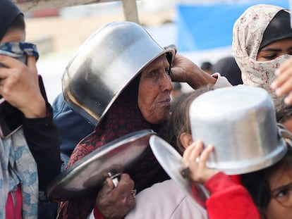 Palestinian women wait for food distribution in a camp for displaced people in Rafah, in the southern Gaza Strip.