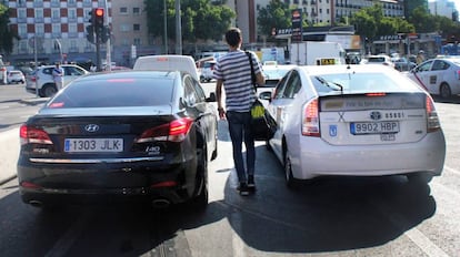 Un viajero camina entre un Vehículo de Alquiler con Conductor y un taxi.