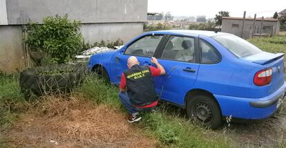 Un agente revista un coche accidentado.