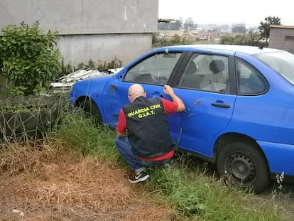 Un agente revista un coche accidentado.