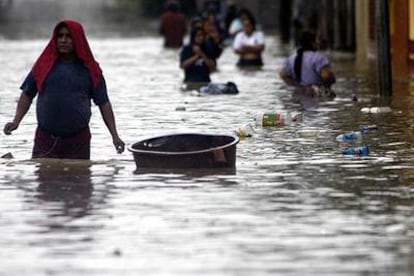 Varias personas caminan entre las aguas del río Suchiate, en la frontera entre Guatemala y México.