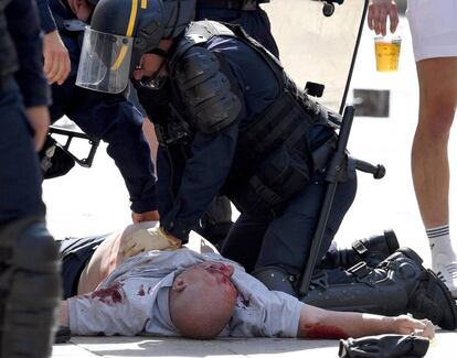 Un polic&iacute;a atiende a un seguidor brit&aacute;nico herido tras el partido Inglaterra-Rusia
