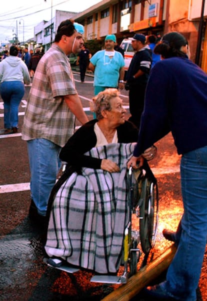 Una mujer es evacuada del centro hospitalario en llamas.