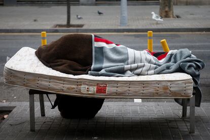 Una persona sin hogar descansa en un banco del barrio de Sant Andreu de Barcelona, el pasado viernes.