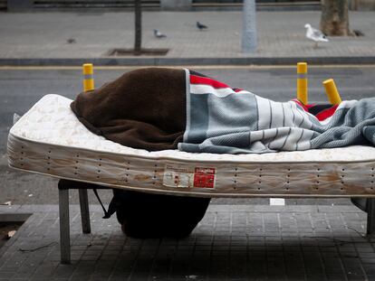 Una persona sin hogar descansa en un banco del barrio de Sant Andreu de Barcelona, el pasado viernes.