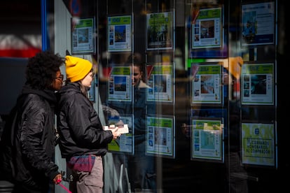 Dos jóvenes, delante del escaparate de una inmobiliaria.