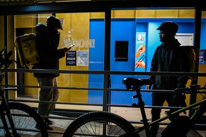 Dos riders esperan la comida para llevar a domicilio en una cocina fantasma en Arganzuela (Madrid), el 29 de diciembre de 2023.