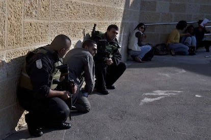 Policías y civiles se refugian en un muro tras la alerta en Jerusalén por el lanzamiento de un cohete desde Gaza.