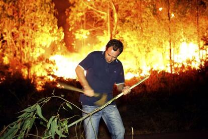 Un vecino prepara una rama para ayudar a atajar el fuego