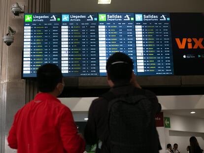 Dos personas miran pantallas con los itinerarios de vuelos en el Aeropuerto Internacional de Ciudad de México, el 13 de abril de 2022.