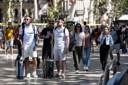 Varios turistas con maletas pasean por Las Ramblas de Barcelona.
