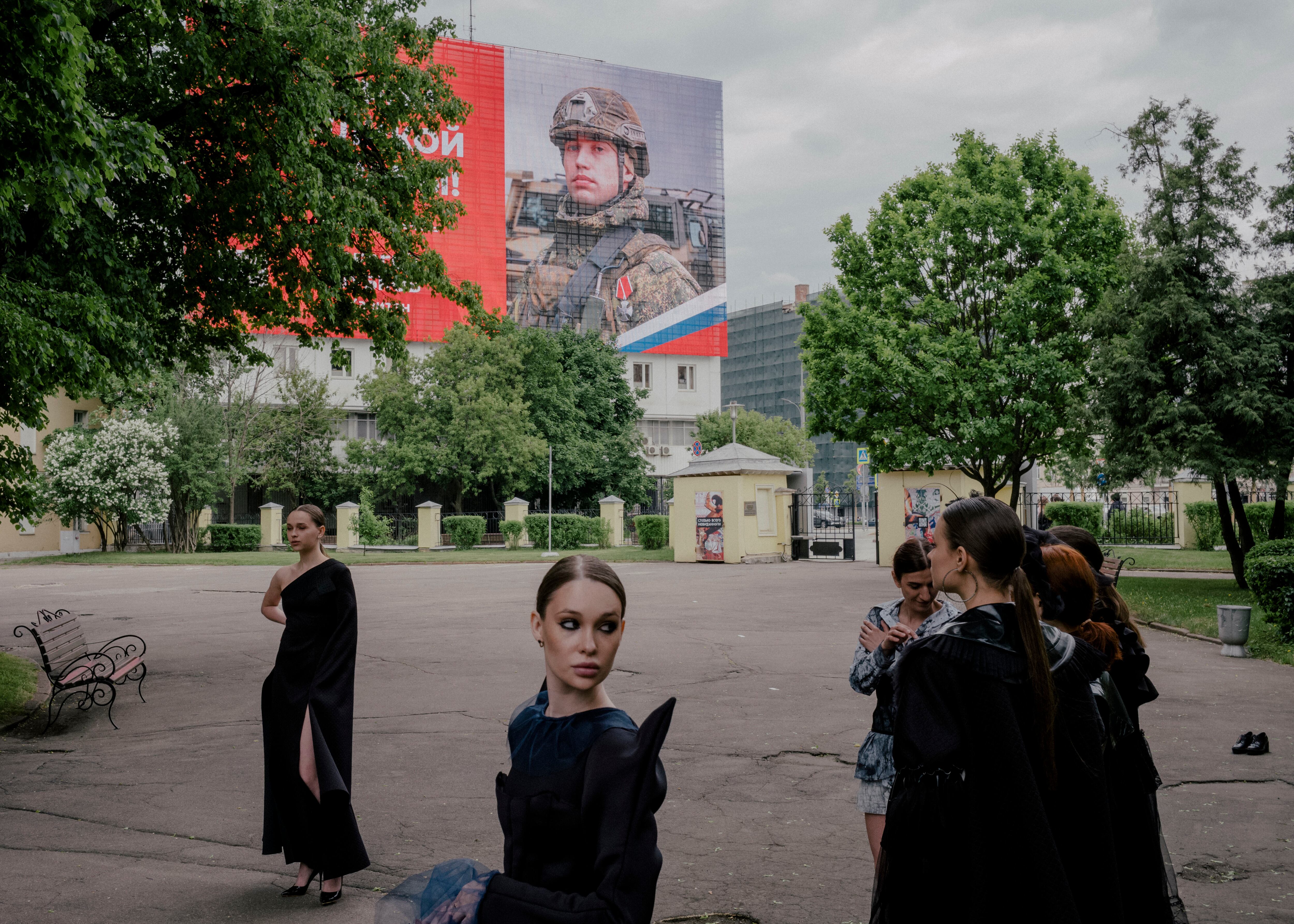 Desfile de moda con un cartel propagandístico del Ejército ruso en el que se lee:  