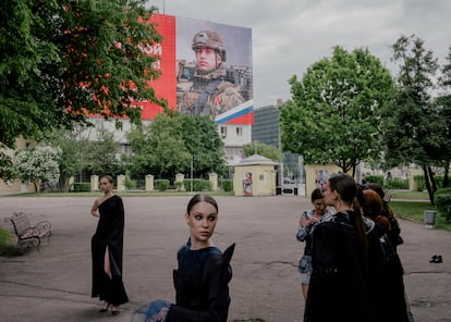 Desfile de moda con un cartel propagandístico del Ejército ruso en el que se lee:  "Héroe de un gran país". Moscú, 20 de mayo de 2023. 