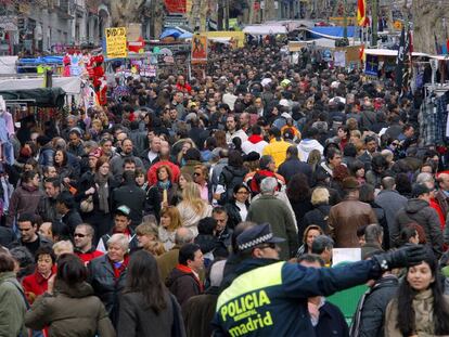 Un policía municipal indica una dirección a un hombre a la entrada del Rastro.