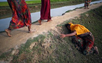 Una mujer rohingya agotada pide ayuda a otros refugiados mientras continúan su camino después de cruzar la frontera de Myanmar y dirigirse a Cox's Bazar (Bangladés).