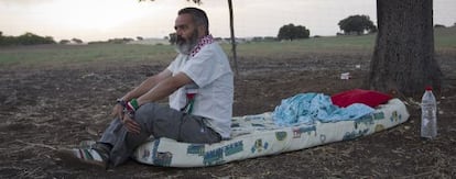 Juan Manuel S&aacute;nchez Gordillo sits on the mattress where he is sleeping on land owned by the Defense Ministry. 