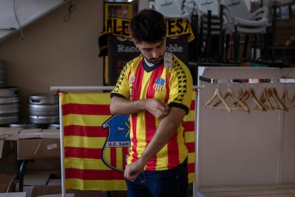 Un aficionado del Sant Andreu se prueba la camiseta del club para comprarla.