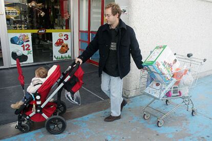 Un hombre, acompañado de un bebé, entra en una establecimiento comercial.