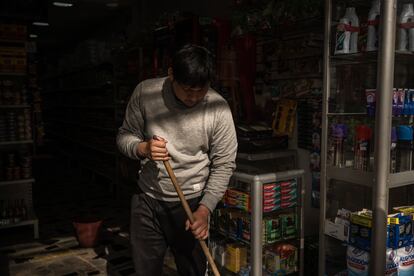 Un joven asea la tienda en Soacha en donde tiene un empleo informal, en mayo de 2023.
