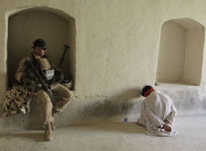 Un <i>marine</i> estadounidense vigila a un detenido en una casa de la aldea de Dahaneh, en la provincia de Helmand (sur de Afganistán).