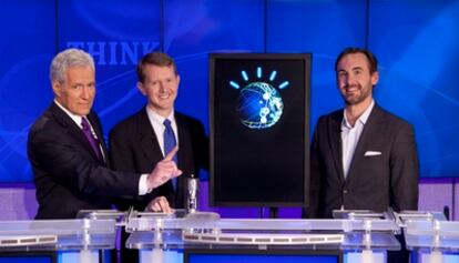 El presentador del programa de preguntas posa junto a los dos humanos que se enfrentan a 'Watson', el robot de IBM, situado en el centro.