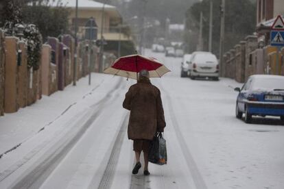 Una mujer camina por una calle nevada en Manzanares el Real esta mañana.