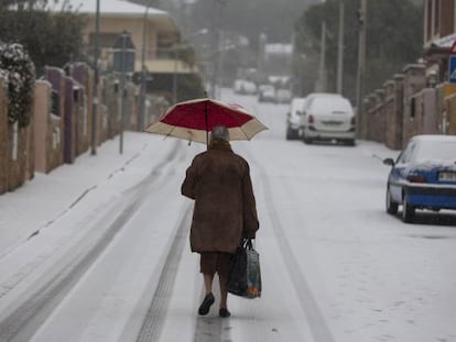 Una mujer camina por una calle nevada en Manzanares el Real esta mañana.
