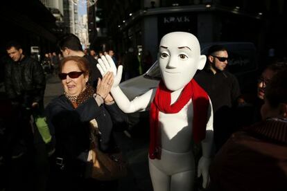 Una señora saluda a uno de los maniquíes de Justino en el centro de Madrid.