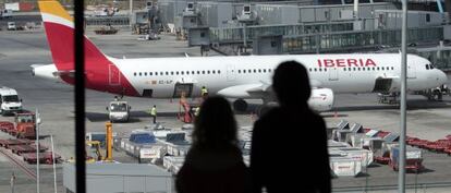 Unos pasajeros observan un avión de Iberia.
