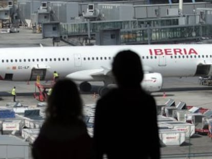 Unos pasajeros observan un avión de Iberia.