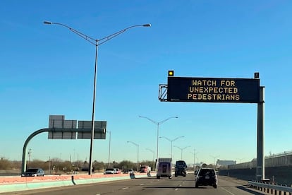 An electronic sign flashes "Watch for unexpected pedestrians," Dec. 20, 2022, on the highway next to the fenced US-Mexican border just east of downtown El Paso, Texas, next to one of the three bridges that connect the Texas city with the sprawling metropolis of Juarez, Mexico.