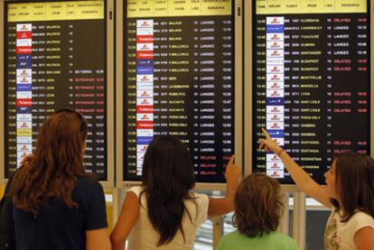 Varios pasajeros se informaban ayer en el panel de vuelos del aeropuerto de Madrid Barajas.