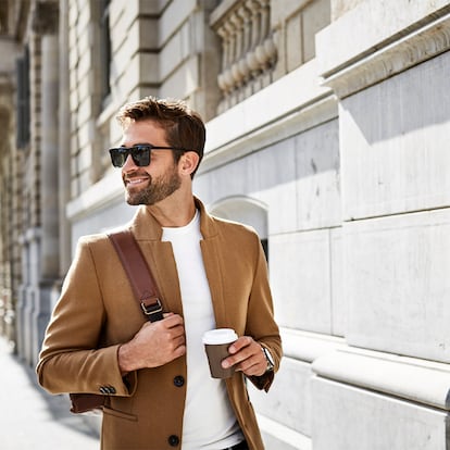 Un hombre con las gafas de sol caminando por la calle.