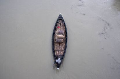 Un aldeano indio utiliza un barco para el transporte de arroz a través del pueblo de Murkata, afectado por las inundaciones en el distrito de Assam Morigoan.