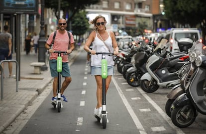 Dos personas se desplazan en patinete eléctrico por un carril bici de Valencia.